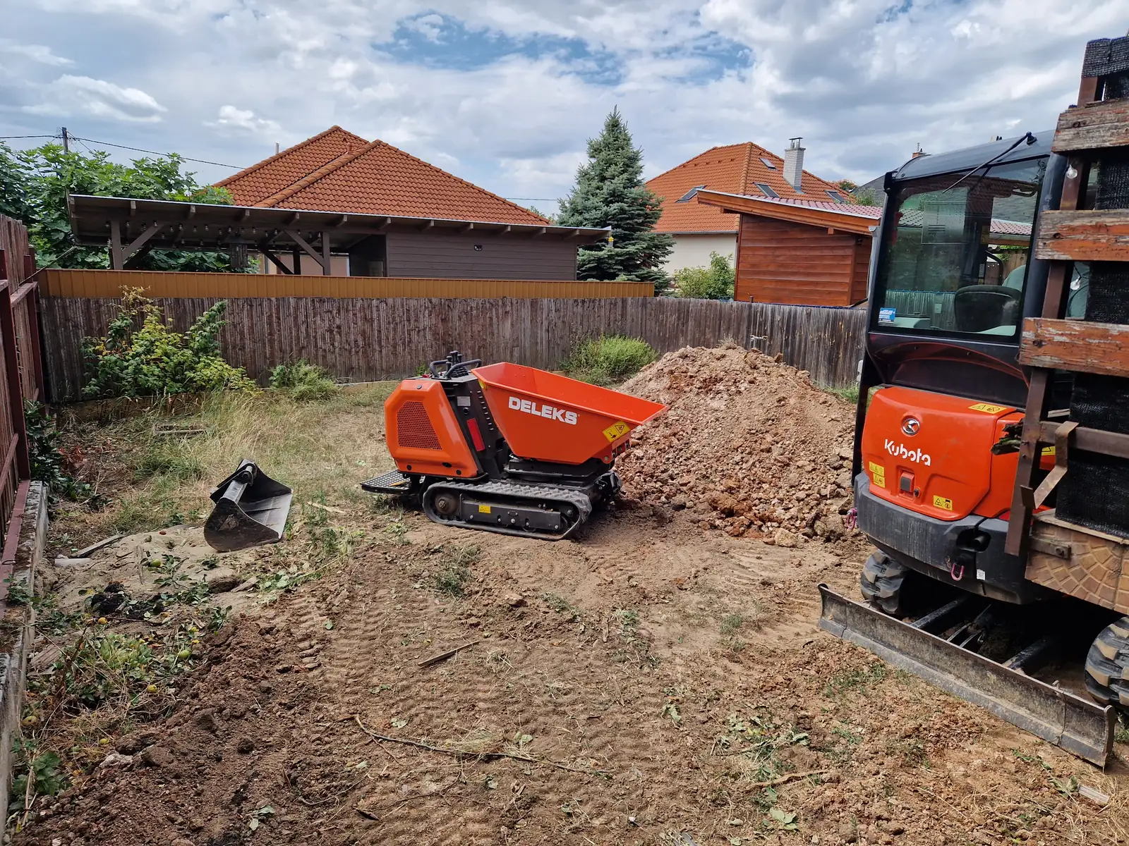 DELEKS M8000R-K lánctalpas minidömper — A kitermelt földet a telken belül mozgatja oda, ahol elfér — lánctalpon, kész gyepen és sárban is. A minikotró közvetlenül ebbe pakol.