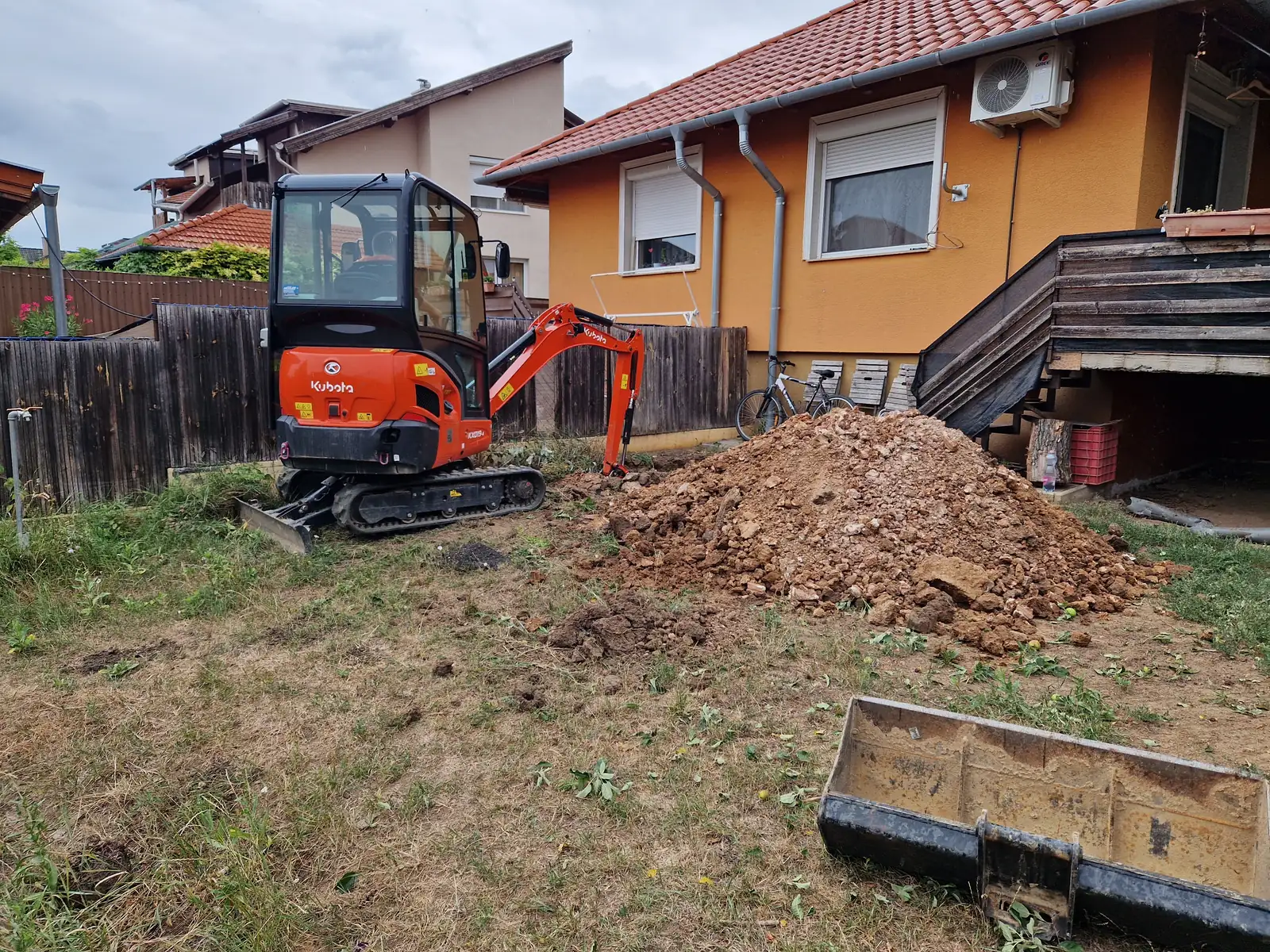 Kubota minikotró családi ház kertjében, mellette a kitermelt föld depóban